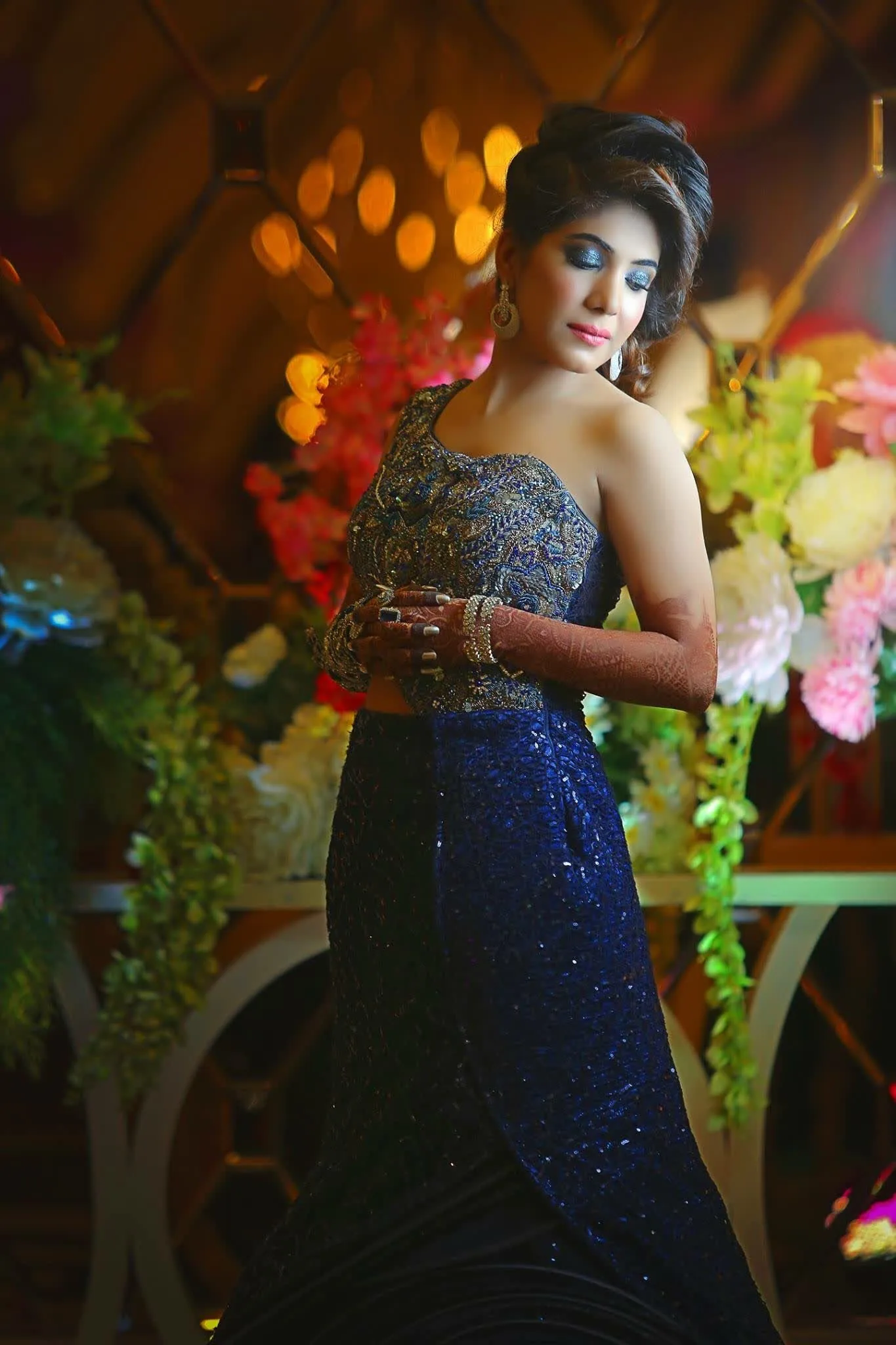 Portrait of a guest in a navy gown beside a flower cart at a wedding reception