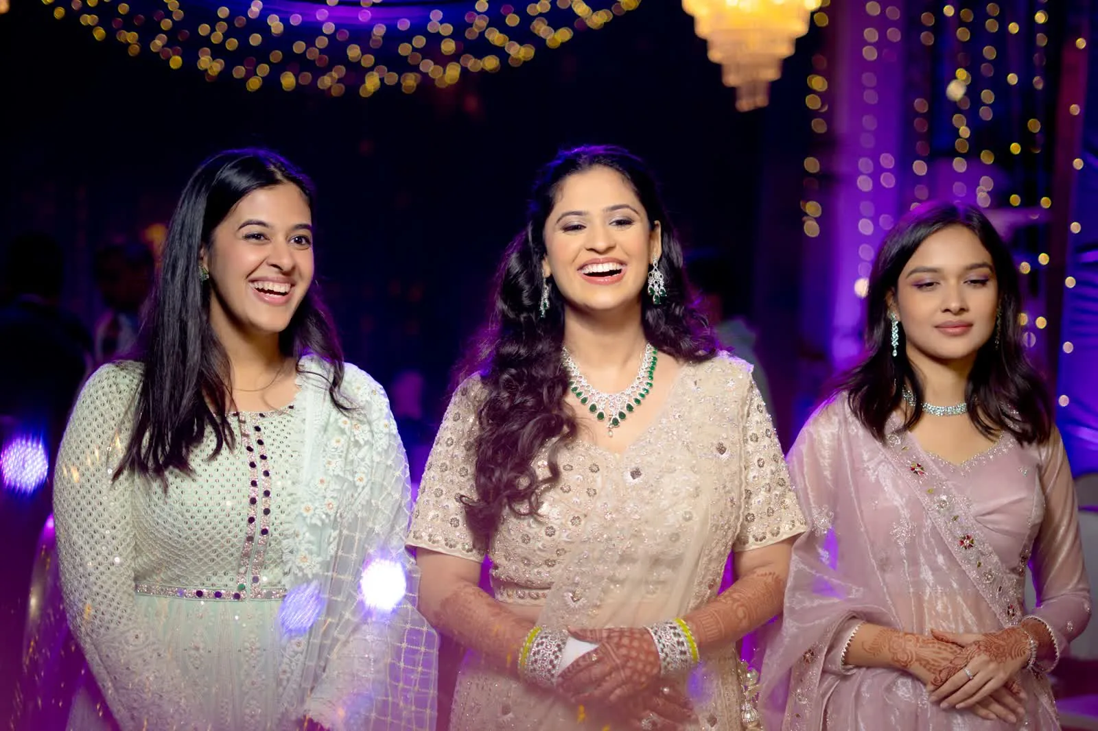 Three guests in pastel outfits photographed candidly at a wedding reception
