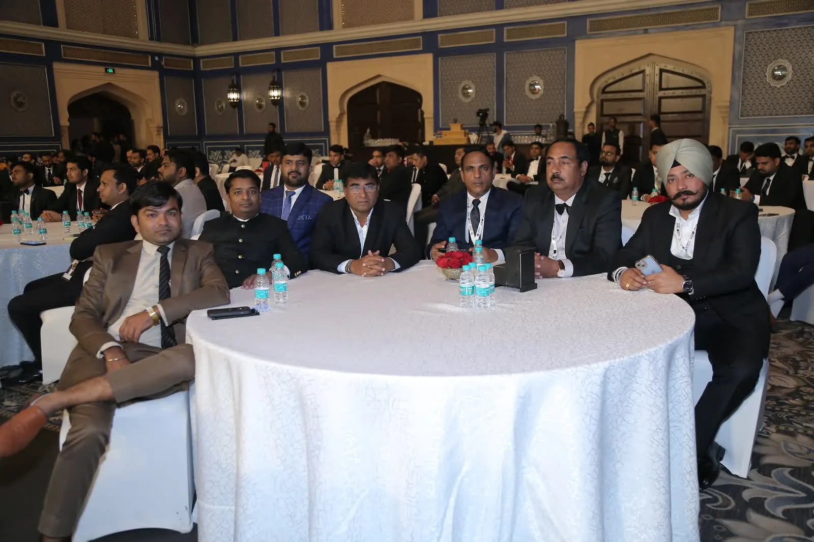 Delegates in suits seated at a round table during a corporate event in Delhi