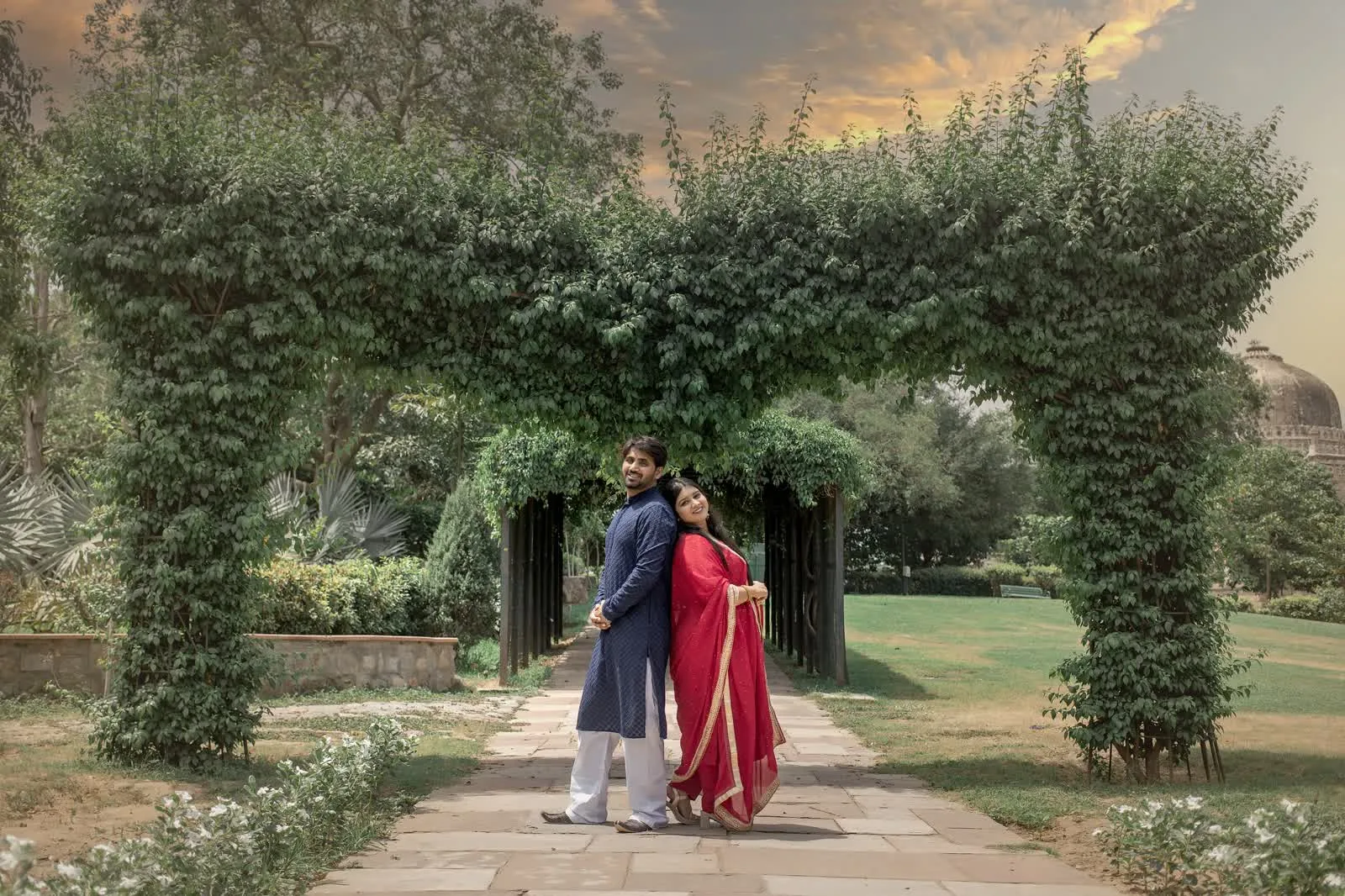 Couple walking a long green arched walkway in a Delhi garden