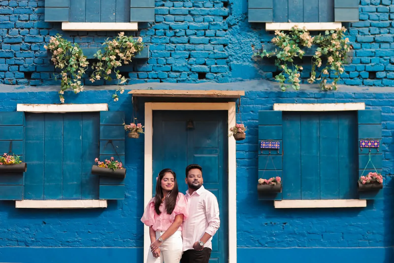 Couple in front of a bright blue painted house, Delhi NCR pre-wedding shoot