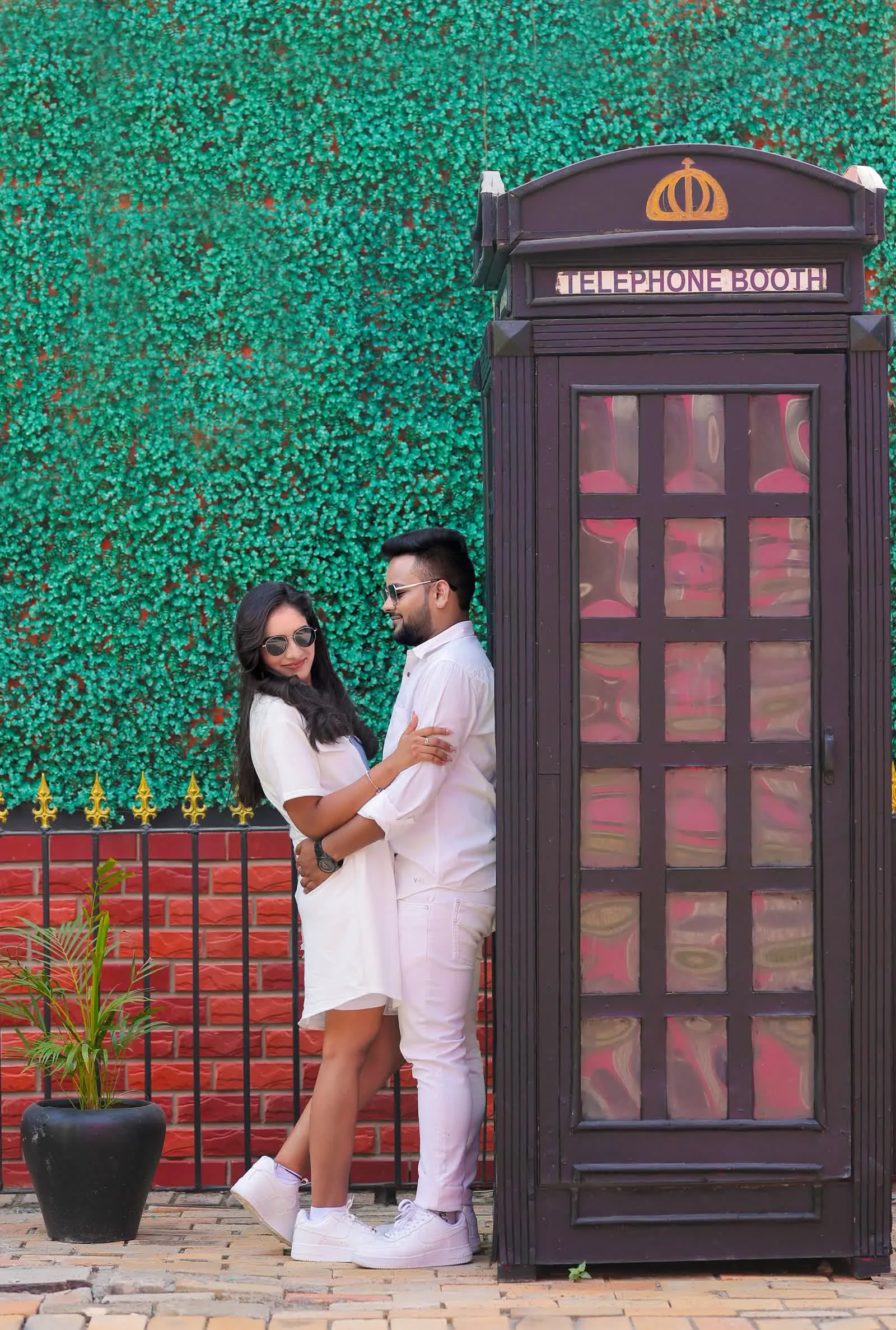 Couple beside a red telephone box against an ivy wall, Delhi pre-wedding shoot
