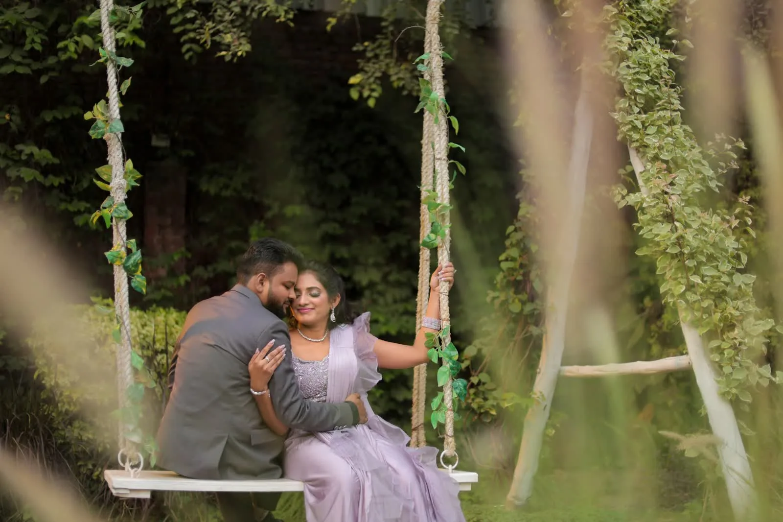 Couple seated on a flower-wrapped garden swing during a pre-wedding shoot